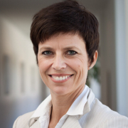 Das Profilbild von Iris Zink bei der Redneragentur PODIUM – Iris Zink lächelt in einem modernen, hellen Büroflur in die Kamera.