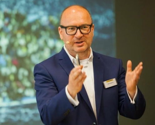 Keynote Speaker Axel Liebetrau mit Präsentation im Hintergrund