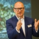 Keynote Speaker Axel Liebetrau mit Präsentation im Hintergrund