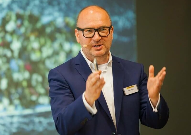Keynote Speaker Axel Liebetrau mit Präsentation im Hintergrund