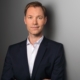 Das Profilbild von Julius van de Laar im Anzug vor grauem Hintergrund bei der Redneragentur PODIUM