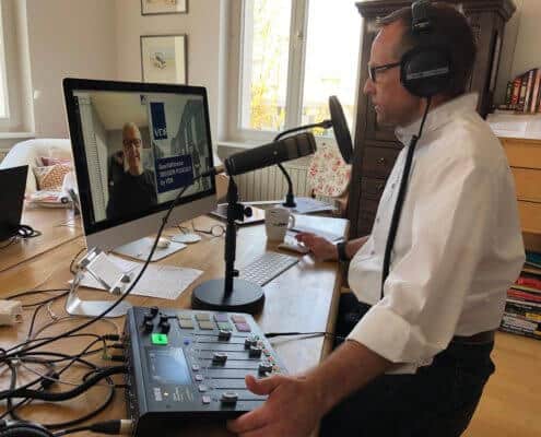 Leif Ahrens sitzt am Schreibtisch und moderiert und produziert einen Podcast