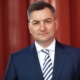 Markus Gürne, Wirtschaftsjournalist und ARD-Börsenexperte, im Portrait vor einem roten Hintergrund.