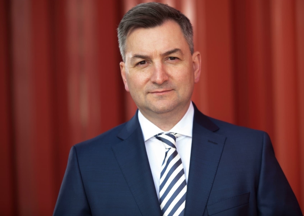Markus Gürne, Wirtschaftsjournalist und ARD-Börsenexperte, im Portrait vor einem roten Hintergrund.