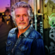 Das Profilbild von Frank Schätzing bei der Redneragentur PODIUM zeigt ihn vor einer urbanen Kulisse mit Graffiti und Sonnenuntergang – ein ausdrucksstarkes Porträt des bekannten Redners.