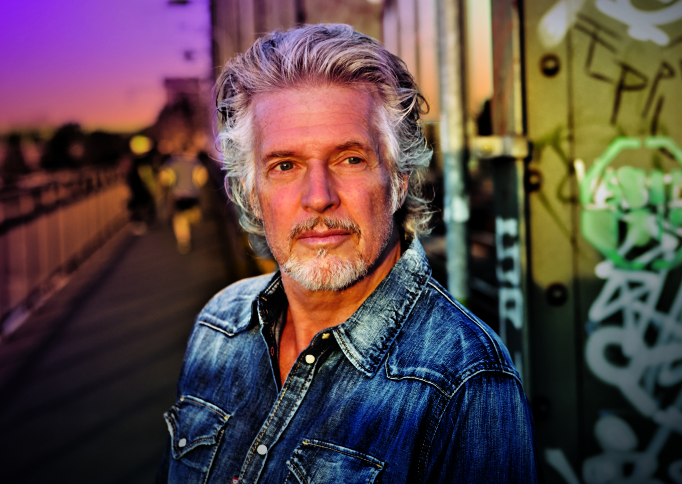Das Profilbild von Frank Schätzing bei der Redneragentur PODIUM zeigt ihn vor einer urbanen Kulisse mit Graffiti und Sonnenuntergang – ein ausdrucksstarkes Porträt des bekannten Redners.