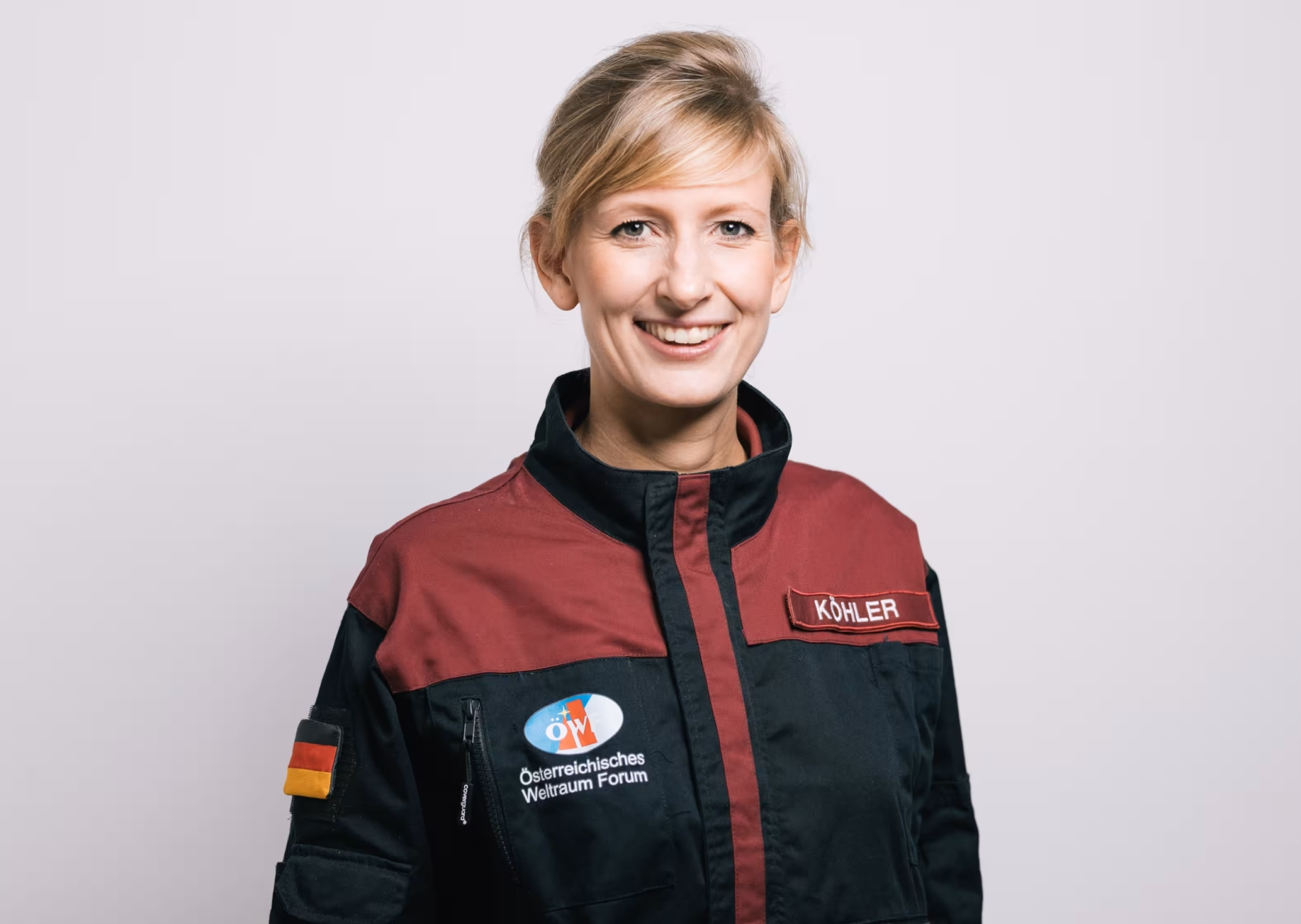 Carmen Köhler – Profilfoto bei der Redneragentur PODIUM in Raumfahrtanzug mit Logo des Österreichischen Weltraum Forums