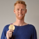Das Profilbild von Jonas Reckermann bei der Redneragentur PODIUM – Jonas Reckermann hält seine olympische Goldmedaille und lächelt in die Kamera.