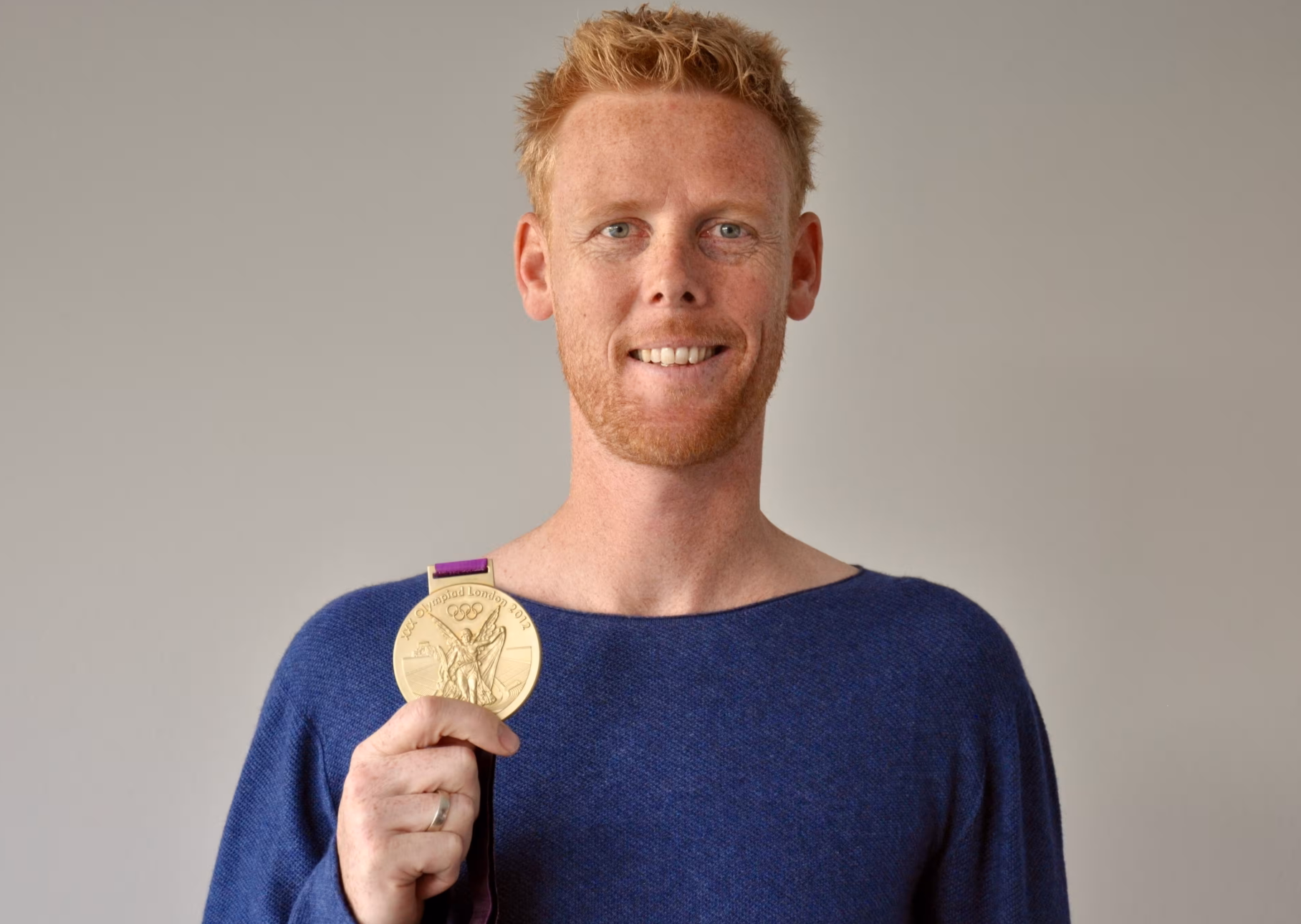 Das Profilbild von Jonas Reckermann bei der Redneragentur PODIUM – Jonas Reckermann hält seine olympische Goldmedaille und lächelt in die Kamera.