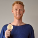 Das Profilbild von Jonas Reckermann bei der Redneragentur PODIUM – Jonas Reckermann hält seine olympische Goldmedaille und lächelt in die Kamera.