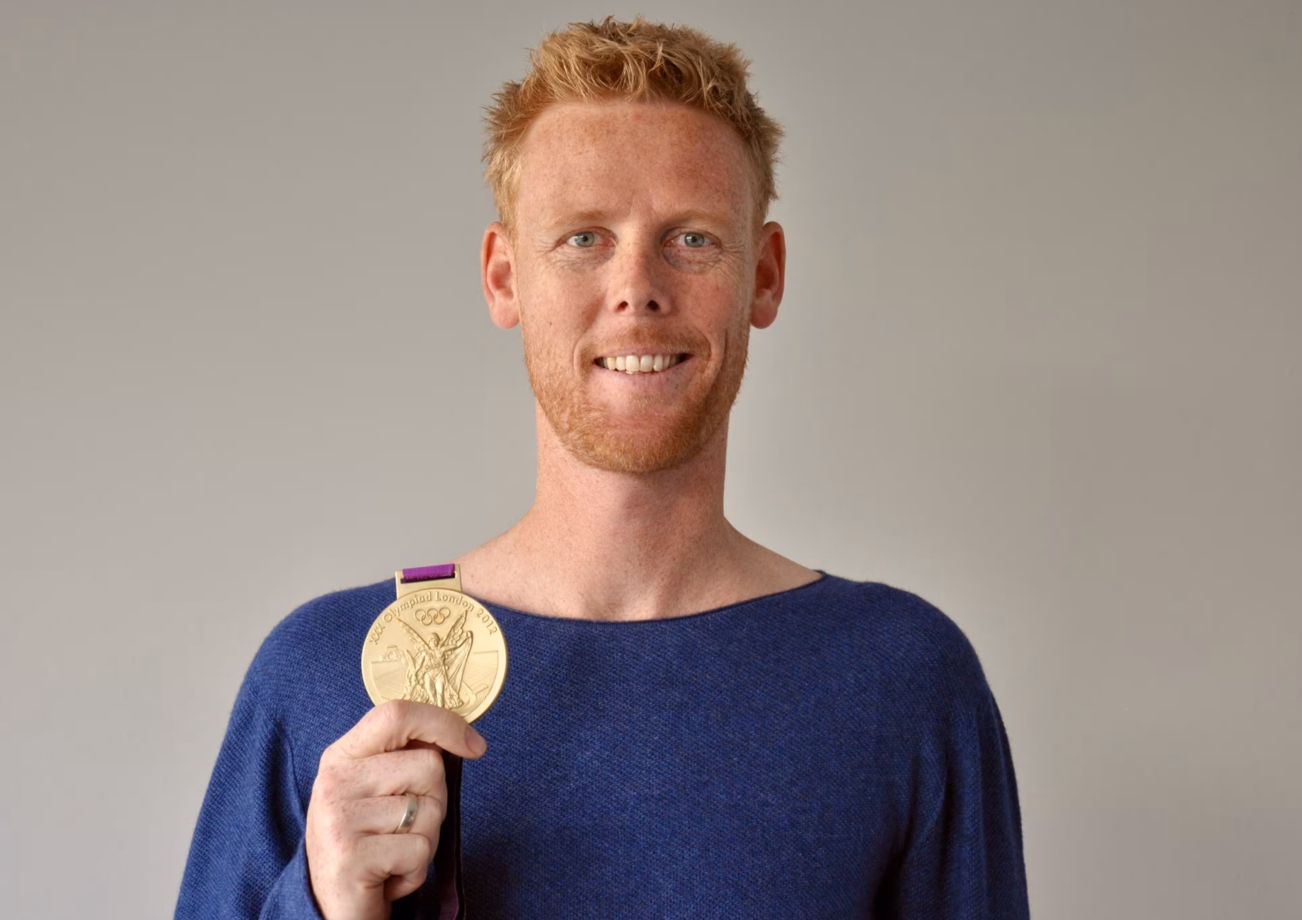 Das Profilbild von Jonas Reckermann bei der Redneragentur PODIUM – Jonas Reckermann hält seine olympische Goldmedaille und lächelt in die Kamera.