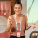 Das Profilbild von Jule Bosch bei der Redneragentur PODIUM – Jule Bosch hält einen Gong und spricht auf einer Bühne.