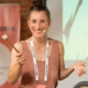 Das Profilbild von Jule Bosch bei der Redneragentur PODIUM – Jule Bosch hält einen Gong und spricht auf einer Bühne.
