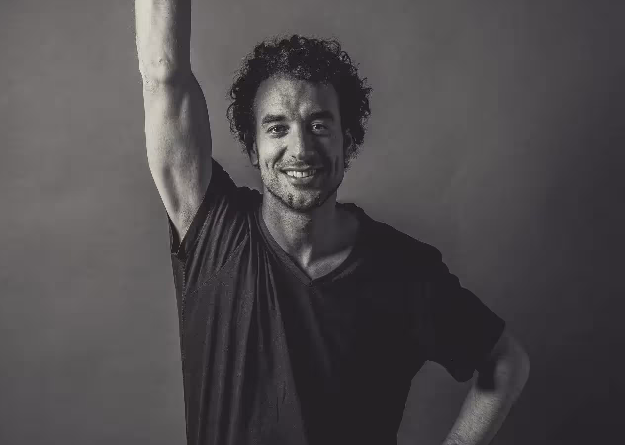 Das Profilbild von Sven Körner bei der Redneragentur PODIUM in Schwarz-Weiß mit erhobenem Arm und freundlichem Lächeln